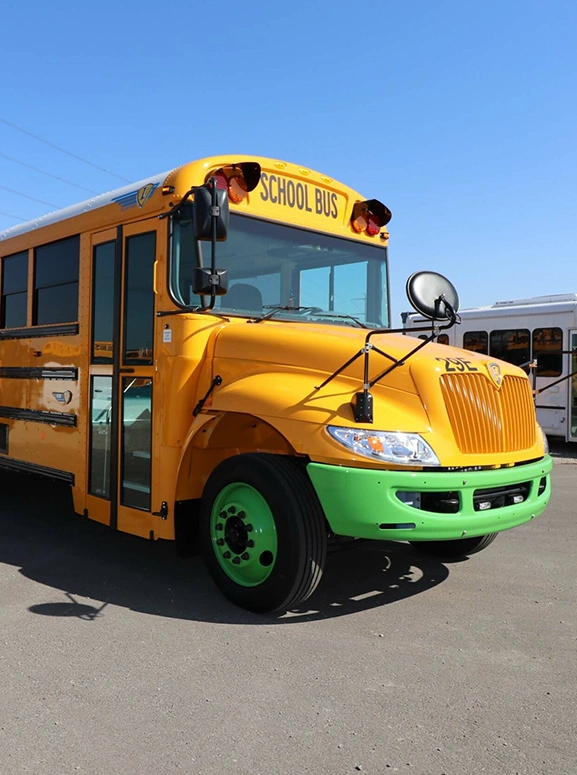 front view of an electric school bus with green bumper and tire caps
